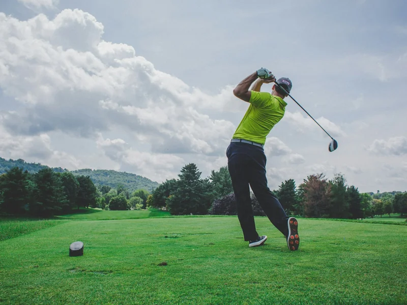 Golfer teeing off on a parkland championship golf course